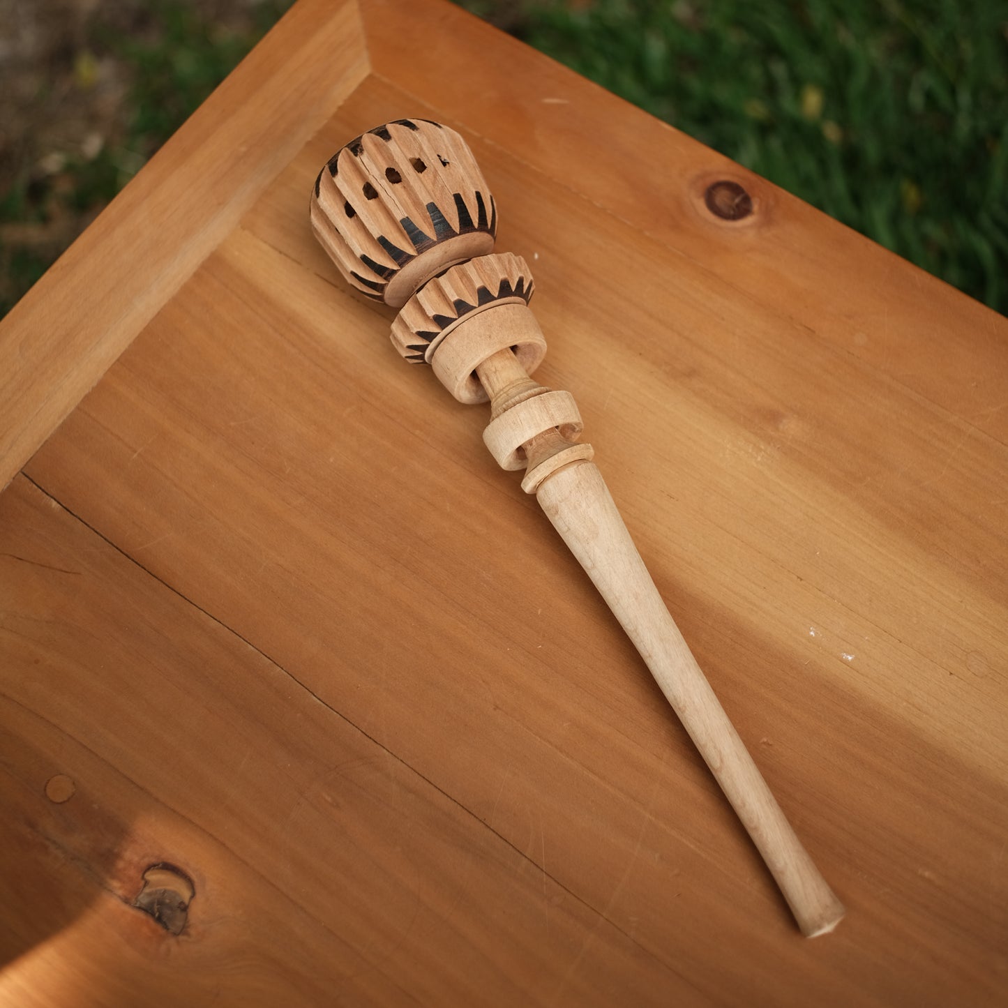 Angled view of artisan molinillo resting on wood surface, molinillo de chocolate, cocoa mixer, ceremonial cacao tool. 