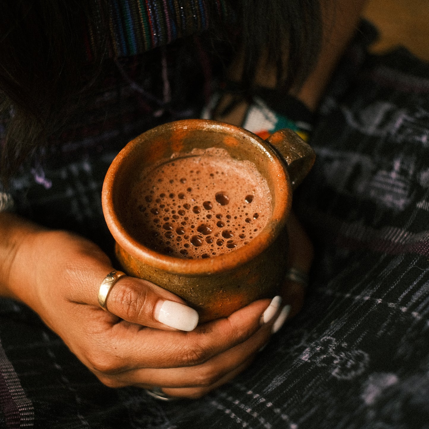 Hand holding ceremonial cacao drink  heart-opening Mayan cacao ritual with cacao whisk