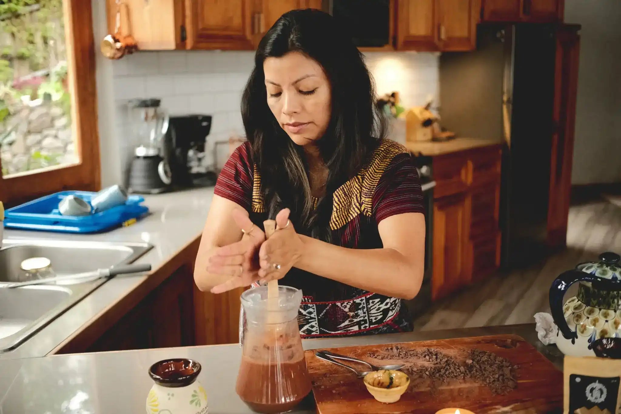 Mayan woman mixing a ceremonial pure cacao drink in a kitchen from mixing raw cacao powder with a liquid